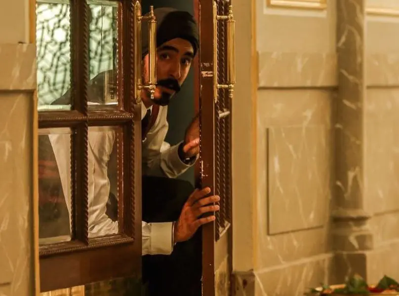 actor dev patel peering through hotel door in hotel mumbai