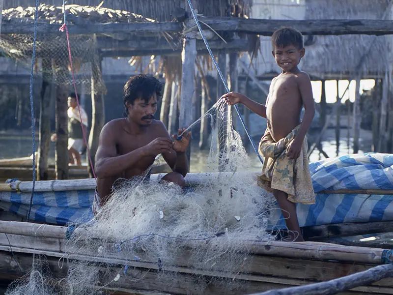 Father and son sea nomads of Indonesia untangle fishing net
