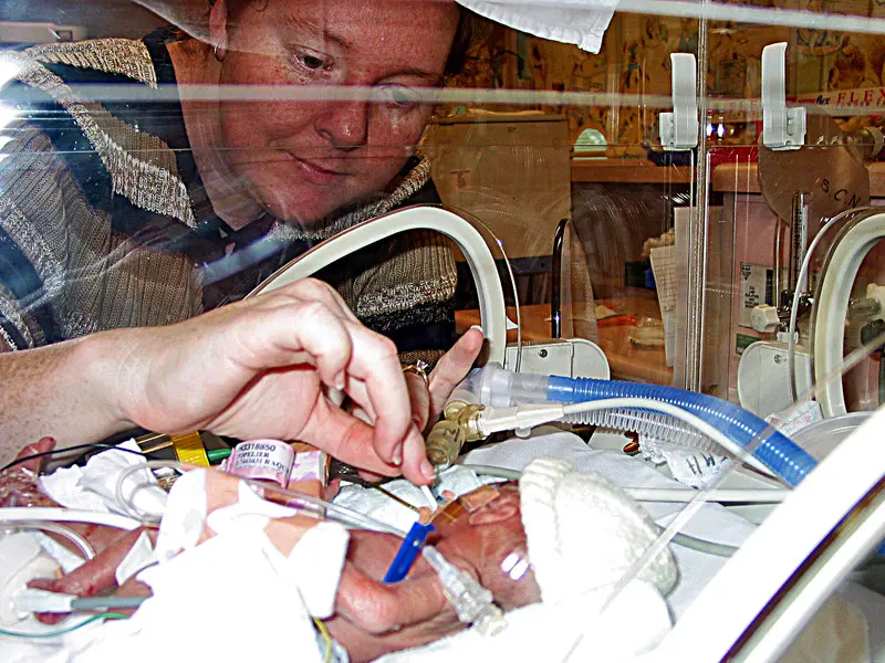 A premature baby is tended to in an incubator in a Children's Hospital