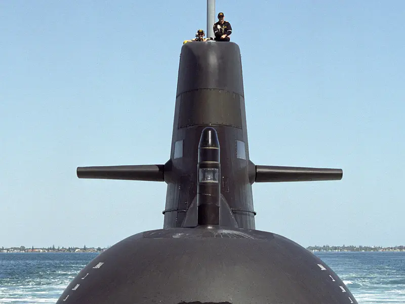 Two submariners sit on fin of the Collins Class Submarine the Rankin in the sea