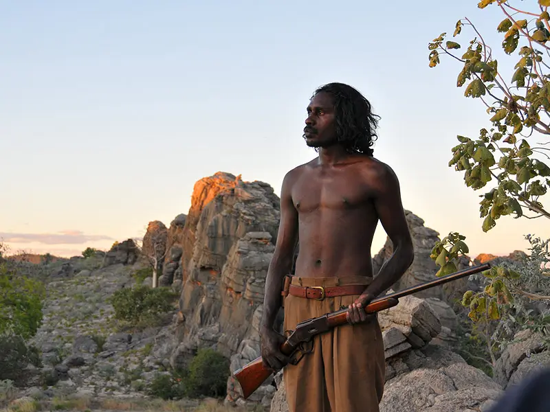 Aboriginal Warrior Jandamarra holding gun in desert landscape