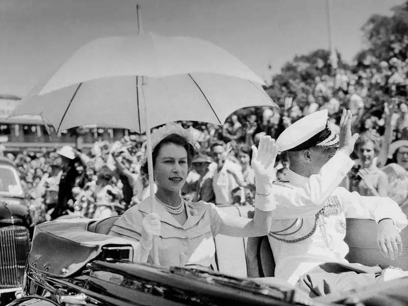 Black and white photo of Queen Elizabeth and Prince Philip waving at crowd from car in Brisbane sunshine parade 1954
